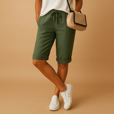 Short en lin vert pour femme, avec cordon de serrage, porté avec un t-shirt blanc et des baskets blanches. Mode estivale décontractée.