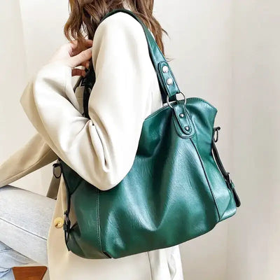 Sac à main en cuir vert élégant porté par une femme en manteau beige, style moderne et chic, accessoire mode tendance pour femmes.