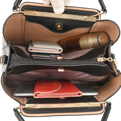 Sac à main ouvert en cuir noir avec compartiments, contenant portefeuille, flacon, smartphone et tablette. Accessoire mode femme, organisation pratique.