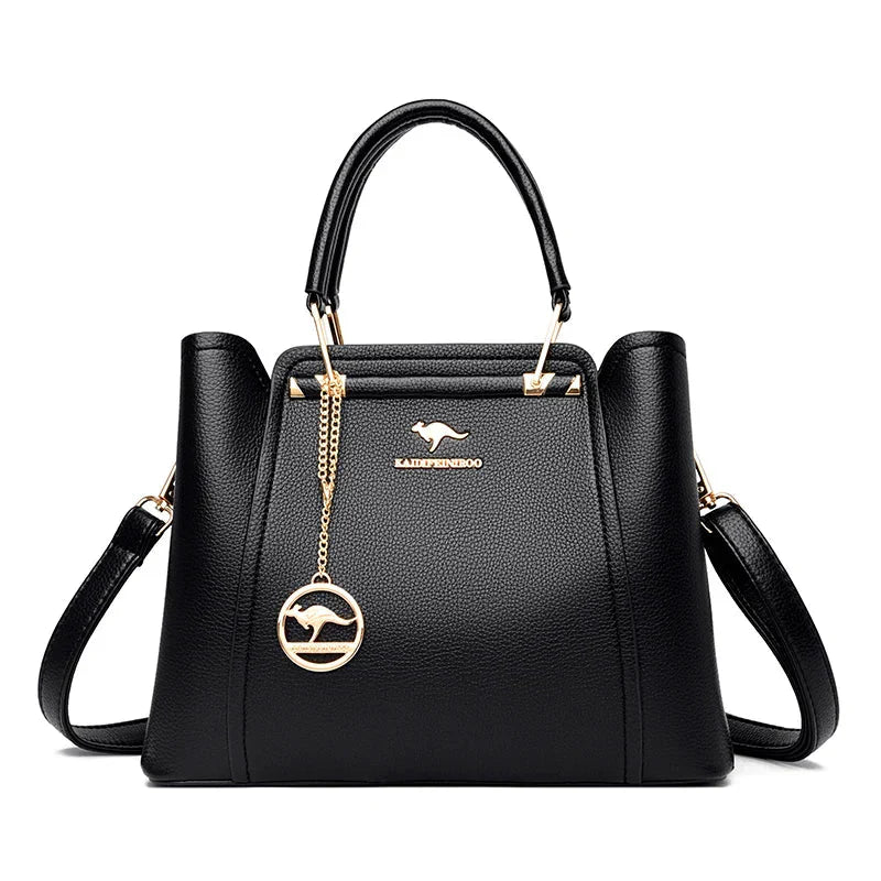 Sac à main noir élégant en cuir avec logo doré, bandoulière amovible et pendentif rond. Accessoire mode femme chic et tendance.