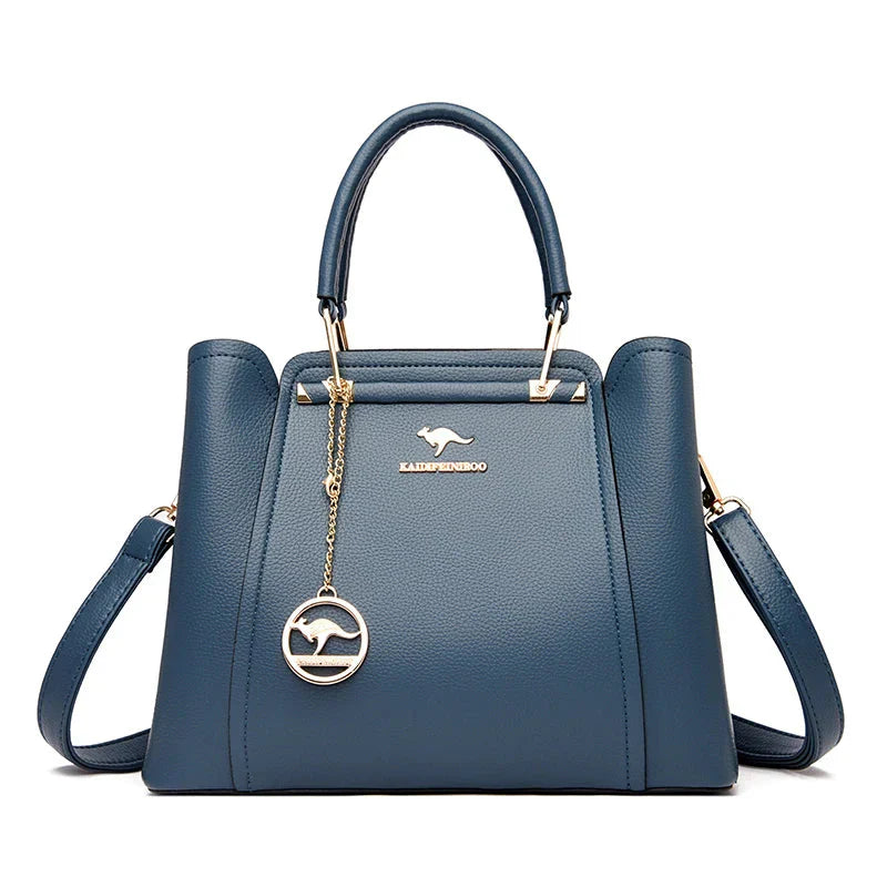 Sac à main bleu en cuir avec bandoulière, logo kangourou doré, design élégant et moderne, idéal pour la mode féminine et les accessoires tendance.