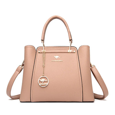 Sac à main en cuir beige élégant avec bandoulière amovible, poignées supérieures, et pendentif doré. Accessoire mode femme chic et tendance.