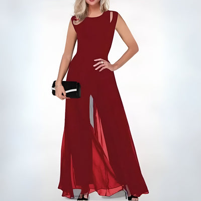 Robe longue rouge élégante avec fente, portée par une femme tenant une pochette noire. Mode soirée chic, tendance et glamour.