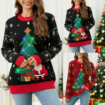 Femme portant un pull de Noël lumineux avec motif sapin et Père Noël, décor festif en arrière-plan. Mode hiver, vêtements de fête, style décontracté.