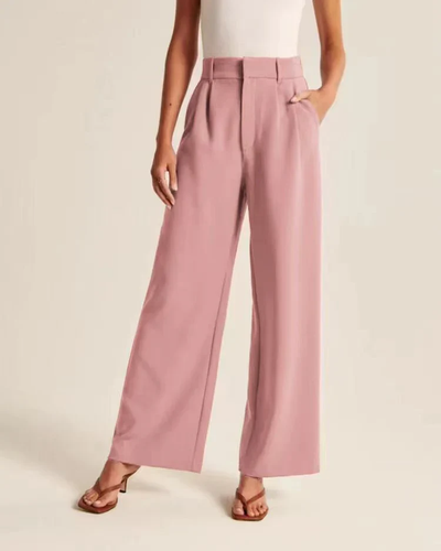 Pantalon large rose femme, taille haute, poches latérales, porté avec un haut blanc sans manches et sandales marron. Mode élégante et tendance.