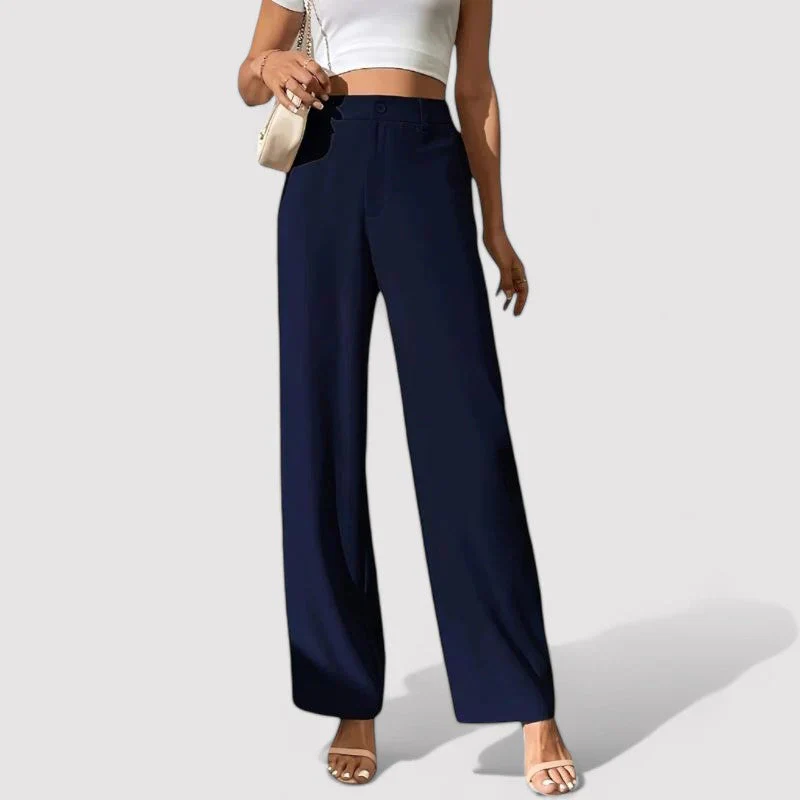 Femme portant un pantalon large bleu marine, haut blanc sans manches, sandales blanches et sac à main beige. Mode élégante et décontractée.