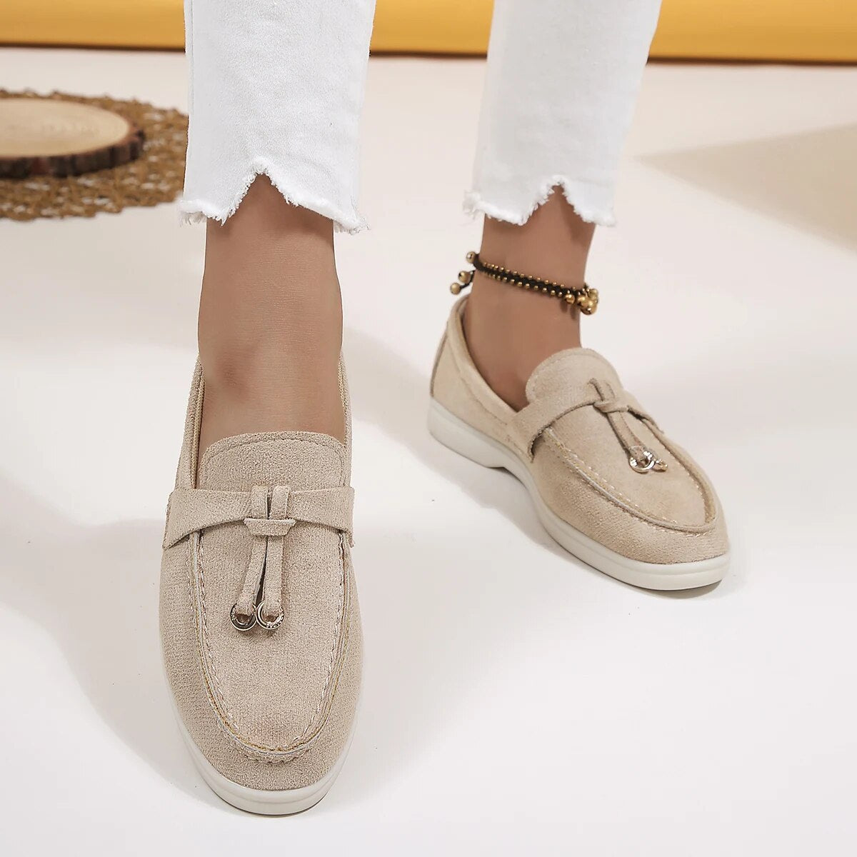 Mocassins beiges en toile pour femme, élégants et confortables, portés avec un pantalon blanc. Chaussures tendance pour un look décontracté.