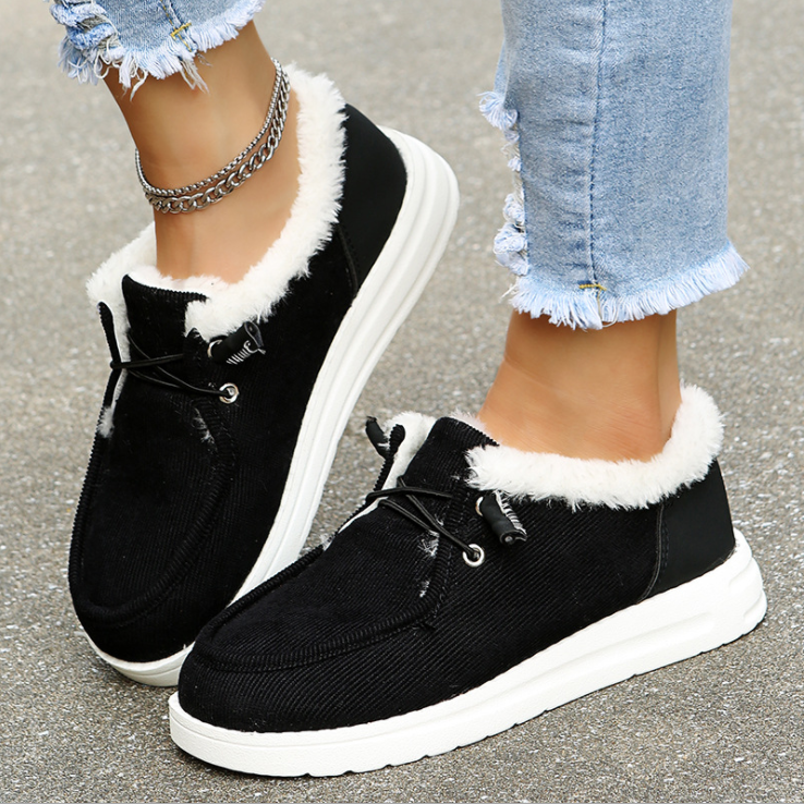 Chaussures noires en daim avec doublure en fourrure blanche, portées avec un jean déchiré. Sneakers tendance pour l'hiver, confortables et stylées.