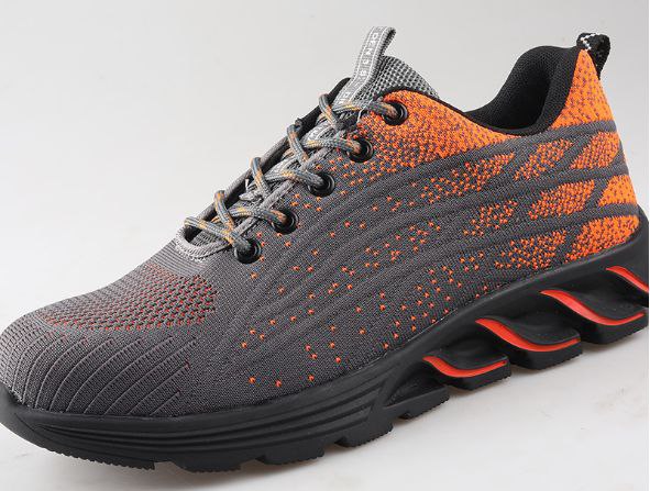 Chaussure de sport grise et orange avec semelle épaisse noire, design moderne et lacets gris. Idéale pour la course et le fitness.
