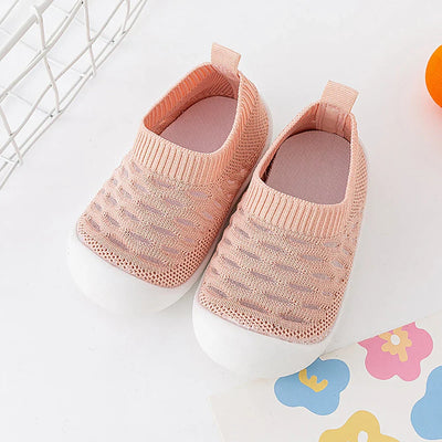 Chaussures bébé roses en maille respirante avec semelle blanche, posées sur fond blanc. Design confortable et moderne pour enfants.