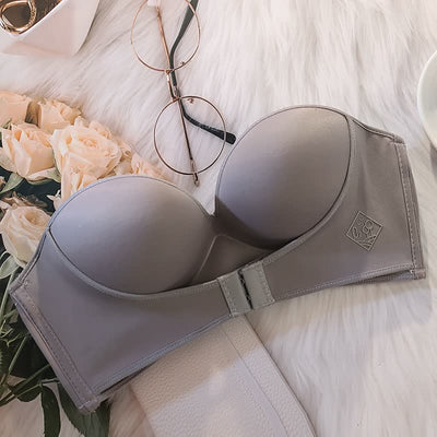 Soutien-gorge gris sans bretelles sur fond de fourrure blanche, avec lunettes et roses. Lingerie féminine élégante, confort et style.
