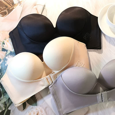 Soutiens-gorge sans bretelles en noir, beige et gris sur fond de fleurs blanches et tasse de café. Lingerie féminine élégante et confortable.