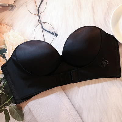 Soutien-gorge noir sans bretelles sur fond blanc, à côté de lunettes et fleurs. Lingerie féminine élégante, accessoire mode essentiel.