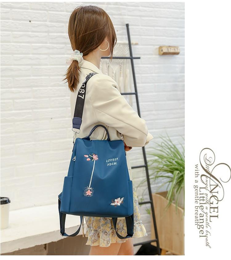 Femme portant un sac à dos bleu avec motifs floraux, style décontracté, intérieur moderne. Accessoire mode tendance pour sorties urbaines.