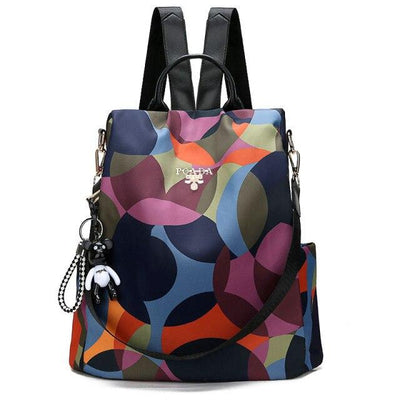 Sac à dos multicolore en tissu imperméable avec motifs géométriques, bretelles ajustables, poignée supérieure et porte-clés décoratif.