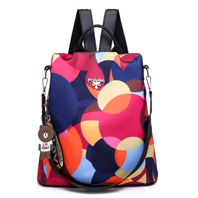 Sac à dos coloré avec motifs géométriques, porte-clés ours, bretelles noires. Idéal pour mode, école, voyage. Accessoire tendance et pratique.