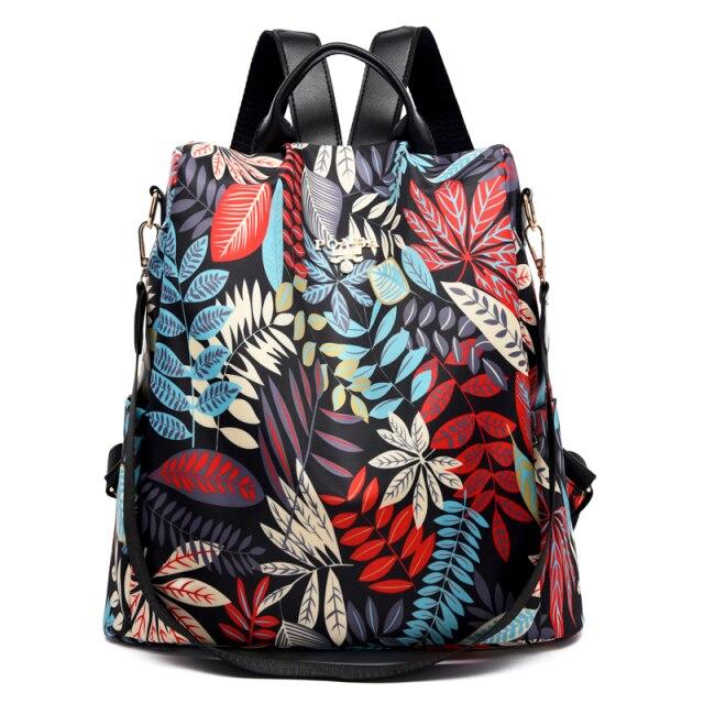 Sac à dos floral coloré avec motifs de feuilles rouges, bleues et beiges, design moderne et élégant, idéal pour la mode et le voyage.