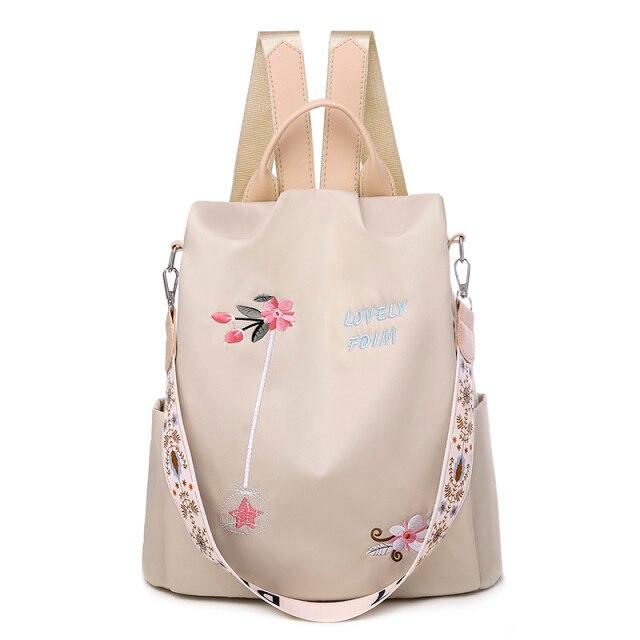 Sac à dos beige élégant avec broderie florale, bandoulière décorative et poignées, idéal pour la mode féminine et le quotidien.