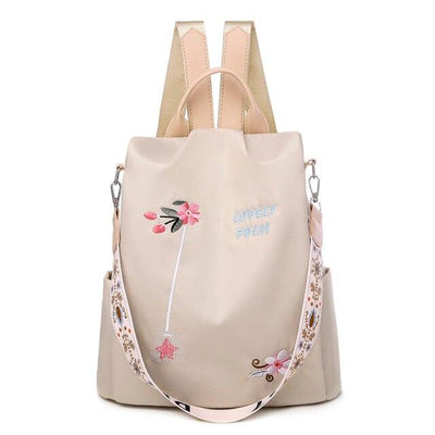 Sac à dos beige élégant avec broderie florale, bandoulière décorative et poignées, idéal pour la mode féminine et le quotidien.