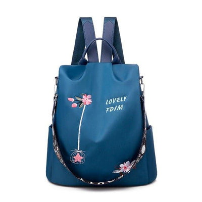 Sac à dos bleu avec motifs floraux roses, texte "Lovely FDM", bretelles ajustables et poignée supérieure. Design élégant et fonctionnel.