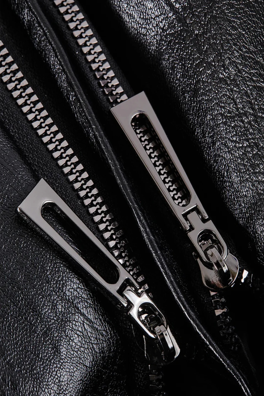 Gros plan sur une fermeture éclair métallique double sur un blouson en cuir noir, texture brillante. Mode, accessoires, vêtements en cuir.