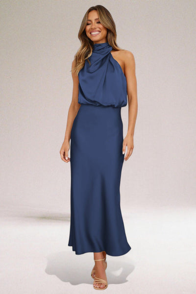 Robe longue bleu marine élégante, col drapé, sans manches, portée par une femme souriante, idéale pour soirées et événements formels.