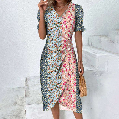 Robe femme à motifs floraux multicolores, manches courtes, col en V, style bohème chic, portée par une femme sur fond d'escalier blanc.