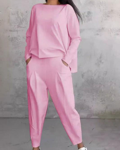Tenue élégante rose pour femme, ensemble deux pièces avec haut ample et pantalon, style décontracté, fond gris minimaliste.