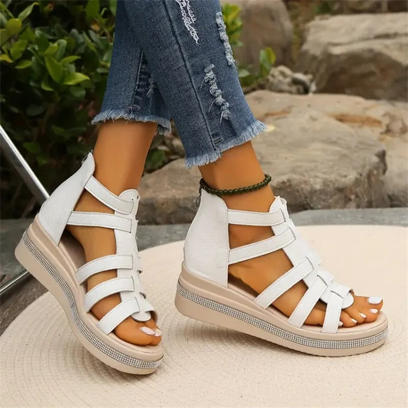 Sandales blanches à plateforme pour femme, style gladiateur, portées avec un jean déchiré. Mode estivale, chaussures tendance, confort et élégance.