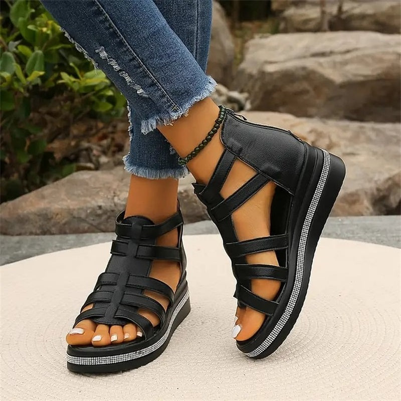 Sandales noires à plateforme pour femme, style gladiateur, portées avec un jean déchiré. Chaussures d'été tendance, confortables et élégantes.