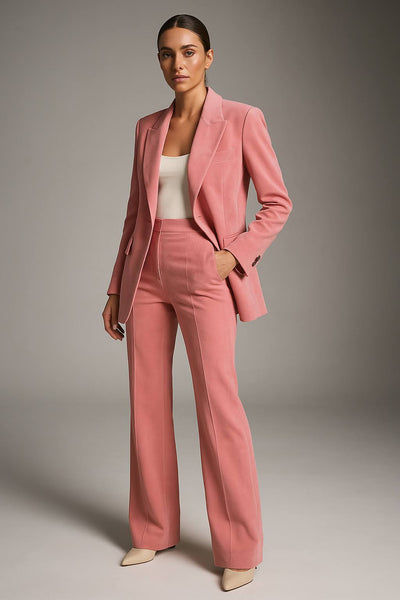 Femme portant un costume rose élégant, veste et pantalon assortis, sur fond neutre. Mode féminine, tenue professionnelle chic, style moderne.