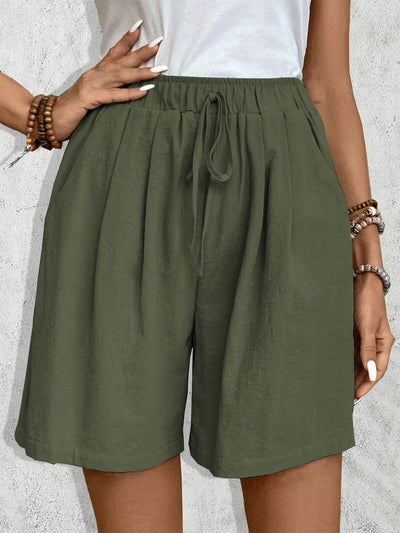 Short vert kaki en lin pour femme avec taille élastique et cordon, poches latérales, porté avec un haut blanc. Mode estivale décontractée.