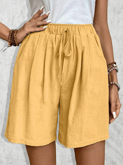 Short en lin jaune pour femme avec taille élastique et cordon, porté avec un haut blanc. Mode estivale, confortable et tendance.