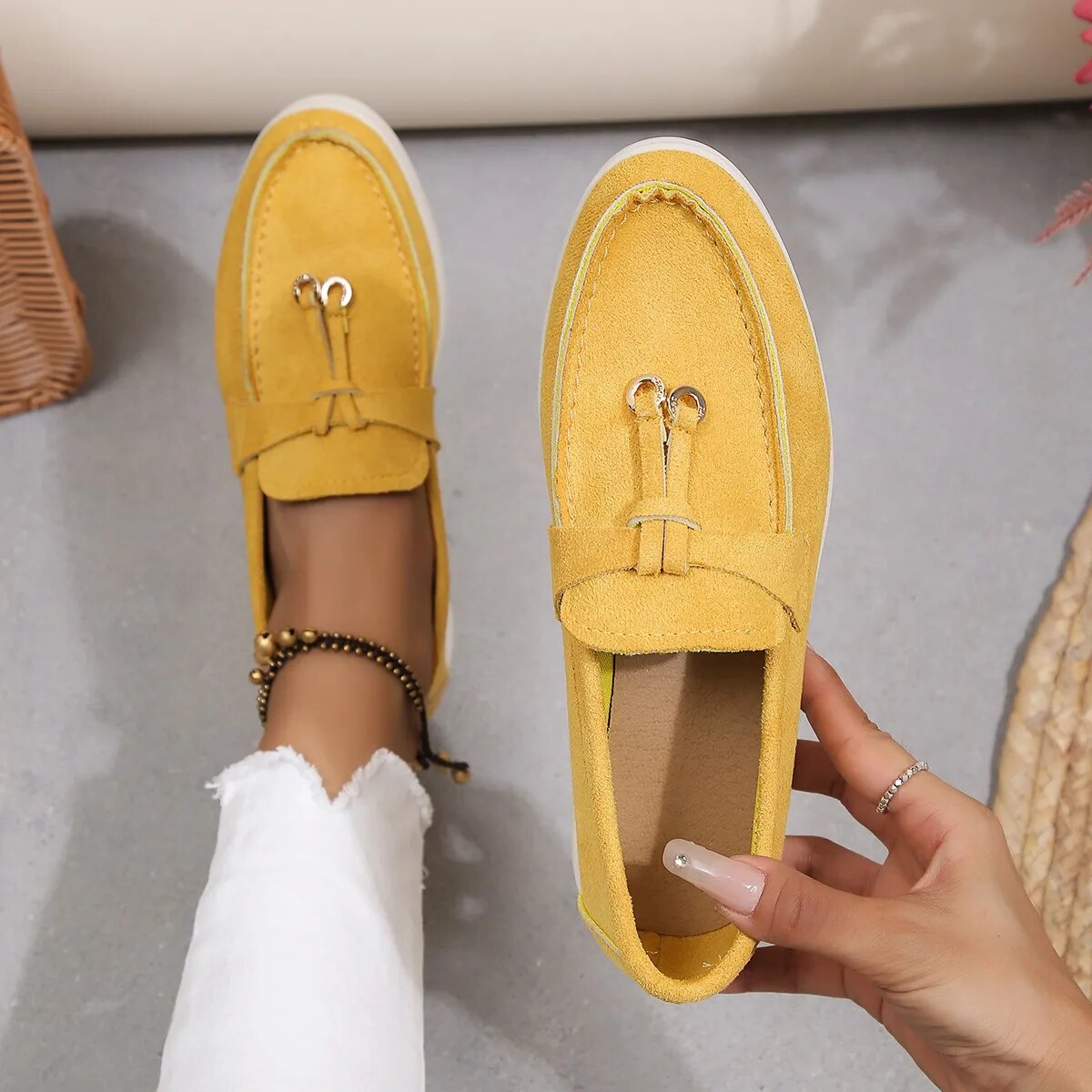 Chaussures mocassins jaunes en daim pour femme, élégantes et confortables, portées avec un pantalon blanc. Mode féminine, style décontracté.